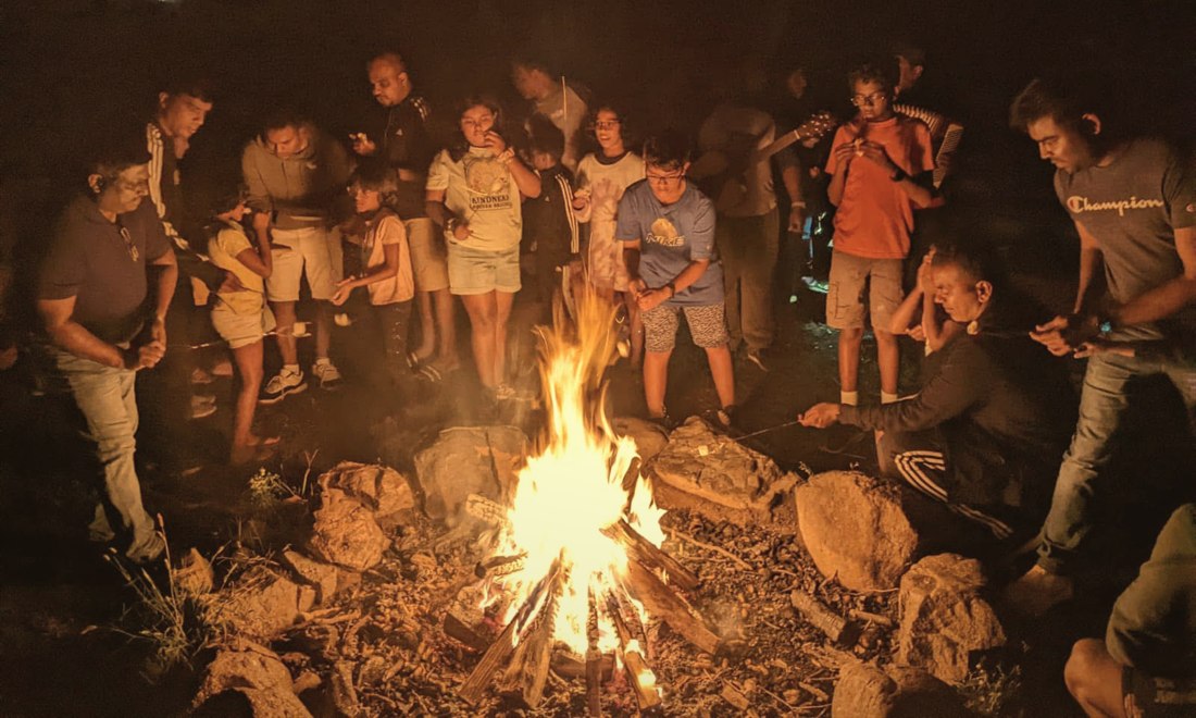 Families and children roasting marshmallows around a campfire at family camp
