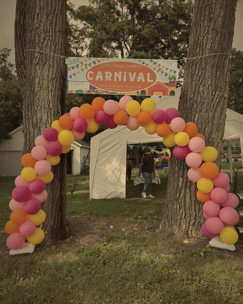 A balloon arch and Christ Tamil Church Carnival banner welcoming families to the summer carnival