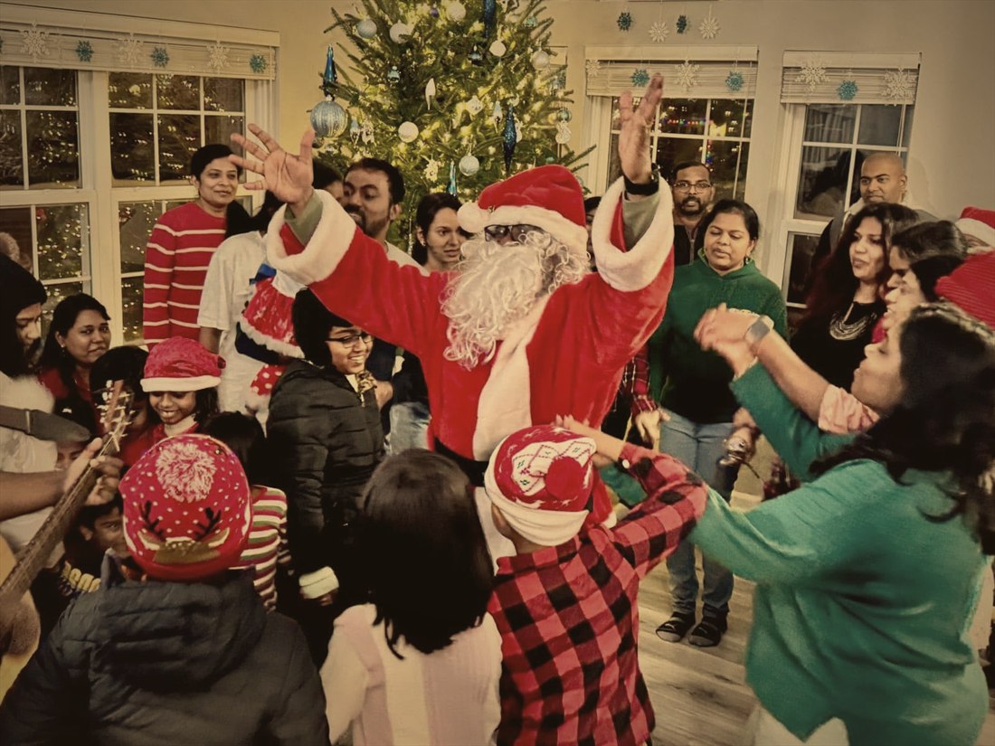 Children and families dancing with Santa beside a Christmas tree during carol rounds