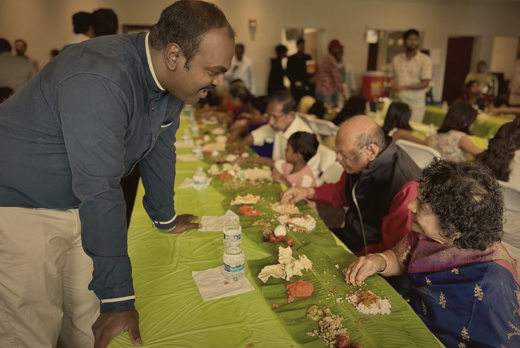 The pastor greeting church members as they share a meal served on banana leaves